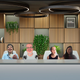 A screenshot of a Zoom call between four Quartz staffers, in which they all appear against one backdrop designed to look like a corporate boardroom. One participant is mostly blurred into the background.